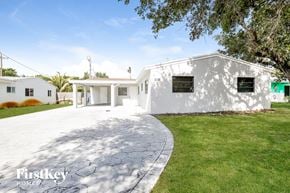 Hollywood house for rent - a white house with a driveway and a lawn