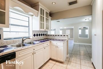Hollywood house for rent - a kitchen with white cabinets and a sink and a window