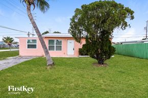 Lake Worth house for rent - A pink house with a palm tree in front.