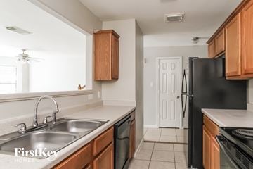 Houston house for rent - a kitchen with wooden cabinets and a sink and a refrigerator