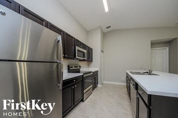Port St. Lucie house for rent - A kitchen with a stainless steel refrigerator and black cabinets.