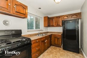 Cincinnati house for rent - full kitchen with black appliances and wooden cabinets and a black refrigerator