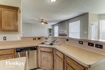 Sachse house for rent - A kitchen with wooden cabinets and a stainless steel dishwasher.