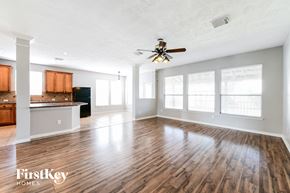 Magnolia house for rent - an empty living room with a ceiling fan and a kitchen