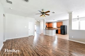 Magnolia house for rent - an empty living room with a ceiling fan and a kitchen