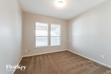 Magnolia house for rent - a spacious living room with carpet and two windows