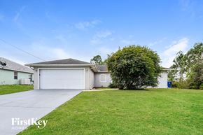 Lehigh Acres house for rent - a white house with a lawn and a white garage door