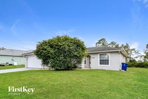 Lehigh Acres house for rent - a white house with a green lawn and a tree