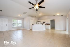 Lehigh Acres house for rent - an empty living room and kitchen with a ceiling fan