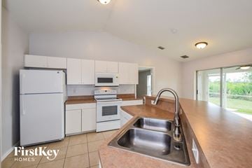 Lehigh Acres house for rent - a kitchen with white cabinets and white appliances and a sink