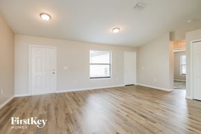 Lehigh Acres house for rent - A spacious room with wooden flooring and white walls, with a window and a door visible.