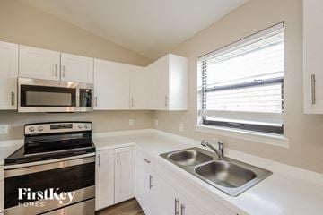 Lehigh Acres house for rent - A kitchen with a stove top oven and a microwave.
