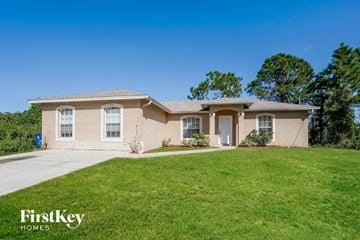 Lehigh Acres house for rent - a beige house with a lawn and a driveway
