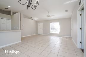 Lehigh Acres house for rent - an empty living room with a kitchen and a ceiling fan