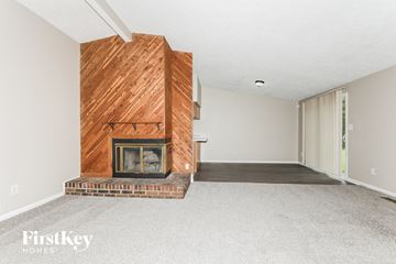 Indianapolis house for rent - a living room with a brick fireplace and a wooden fireplace mantel and a carpet