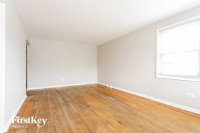 Blue Island house for rent - a bedroom with wood floors and white walls and a window