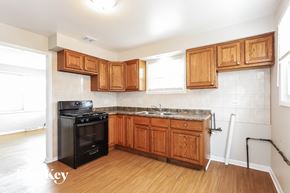 Blue Island house for rent - an empty kitchen with wooden cabinets and black appliances