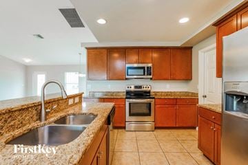 Cape Coral house for rent - A kitchen with wooden cabinets and a granite countertop.
