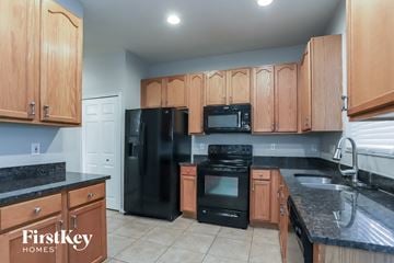 Tarpon Springs house for rent - a kitchen with black appliances and wooden cabinets