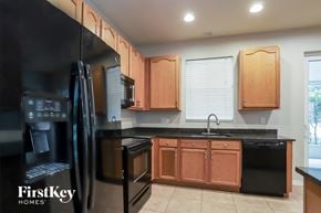 Tarpon Springs house for rent - a kitchen with wooden cabinets and black counter tops and black appliances