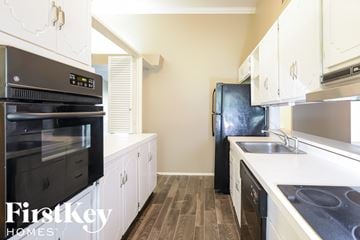Florissant house for rent - A kitchen with a black fridge and a black oven.