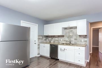 St. Petersburg house for rent - a kitchen with white cabinets and a sink and a refrigerator