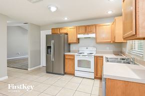 Saint Cloud house for rent - a kitchen with wooden cabinets and white appliances and a stainless steel refrigerator