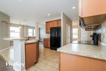 Kissimmee house for rent - a kitchen with an island and a black refrigerator
