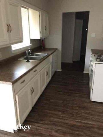 Garland house for rent - a kitchen with white cabinets and a stove and a sink