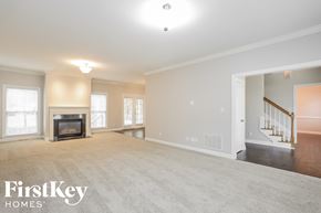 High Point house for rent - A spacious living room with a fireplace and a staircase in the background.