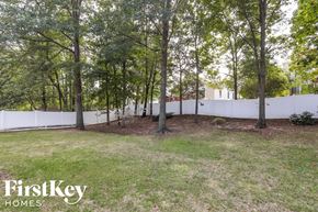 High Point house for rent - A white fence encloses a grassy yard with trees.