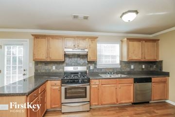 Douglasville house for rent - a kitchen with wooden cabinets and a stove and a sink
