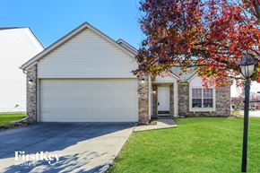 Indianapolis house for rent - A house with a garage and a tree with red leaves in front of it.