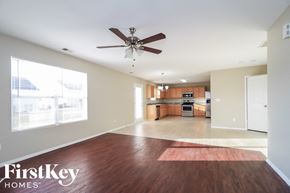 Winston-Salem house for rent - A spacious living room with a wood floor and a ceiling fan.