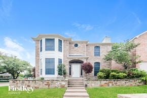 Rockwall house for rent - A large house with a stone wall and a white door.