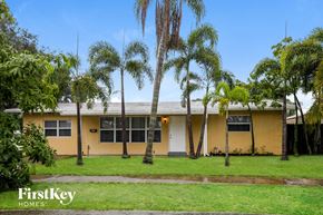 Fort Lauderdale house for rent - a yellow house with palm trees in front of it