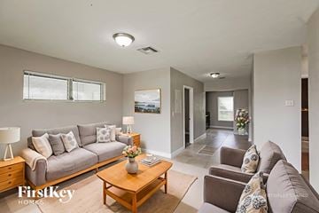 Lauderhill house for rent - A well-lit living room with a grey sofa, wooden coffee table, and a painting on the wall.