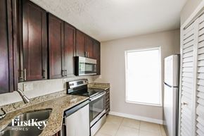 Lauderhill house for rent - A kitchen with brown cabinets and a white refrigerator.