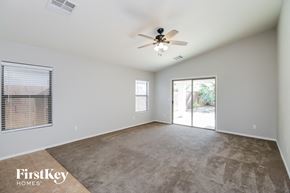 Queen Creek house for rent - an empty living room with a ceiling fan and a door to a patio