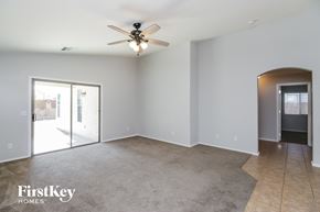 Queen Creek house for rent - an empty living room with a ceiling fan and a door to a patio