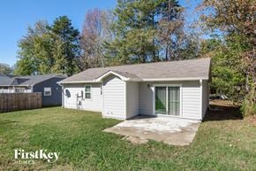 Monroe house for rent - A small house with a grey roof is surrounded by trees and grass.