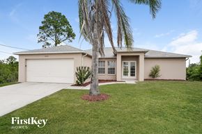 Lehigh Acres house for rent - a beige house with a palm tree in the yard