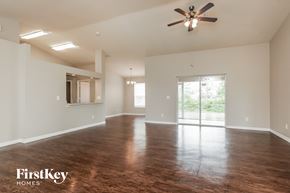 Lehigh Acres house for rent - an empty living room with wood floors and a ceiling fan