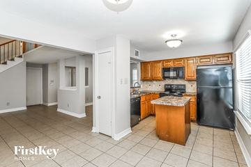 Humble house for rent - a kitchen with black appliances and wooden cabinets
