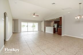 Cape Coral house for rent - an empty living room with a kitchen and a ceiling fan