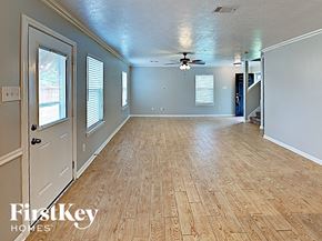 Pinehurst house for rent - an empty living room with a wood floor and a ceiling fan