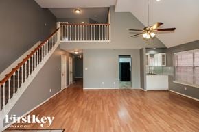 Missouri City house for rent - A spacious living room with a staircase and a ceiling fan.