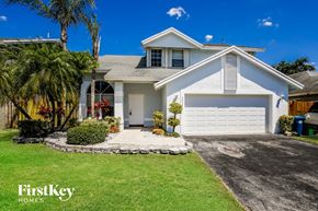 Sunrise house for rent - a white house with a white garage door and a lawn