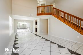 Sunrise house for rent - a staircase in the center of a house with white tile floors and a wooden railing