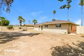 Tempe house for rent - A house with a brown roof and a brown door is surrounded by palm trees.